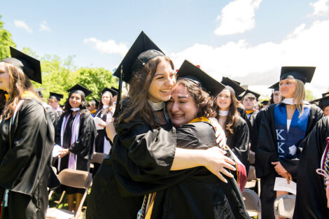Two graduates embrace in a hug.