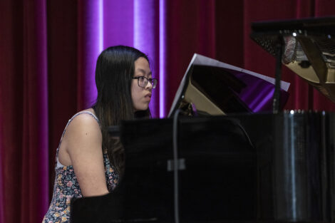 A student plays piano on stage.