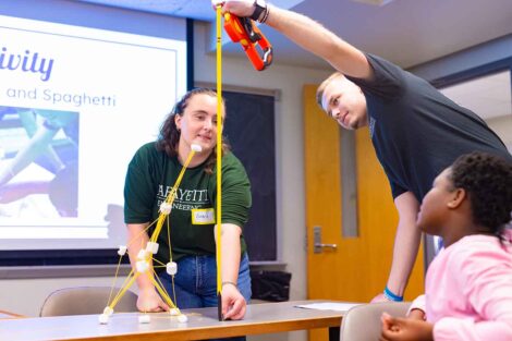 Laf engineering students measure the height of a spaghetti/marshmallow structure.
