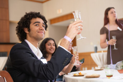 A student raises a glass during a toast.