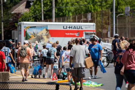 The crowd explores items during the West Ward Sale. A U-haul truck is pictured in the background.