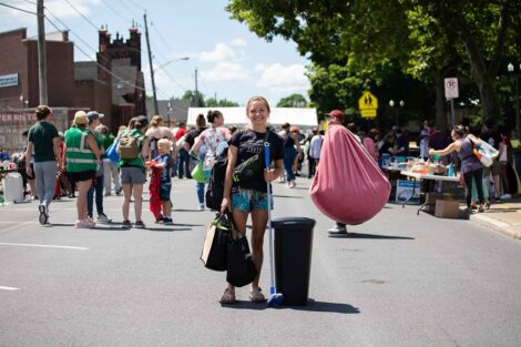 A student holds up a mop, a garbage can, and bags of things found at the West Ward sale