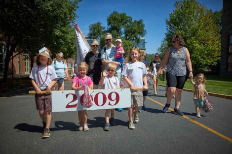 A group of four children are walking in the parade holding a 2009 sign.