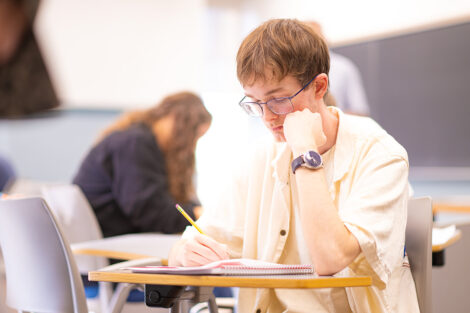 A student writes at their desk