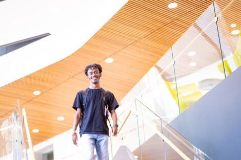 A student smiles walking down a staircase in Rockwell Integrated Sciences Center.