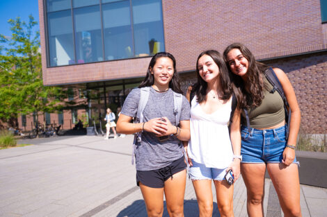 Three students smile in front of Rockwell.