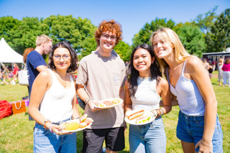 Students smile, holding plates of food.