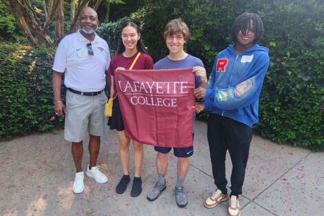 Incoming members of the Class of 2028 from Atlanta are smiling at the camera . They are holding a Lafayette flag.