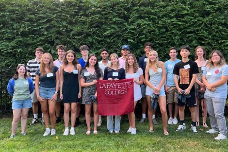 Incoming members of the Class of 2028 from central New Jersey area are smiling at the camera. They are holding a Lafayette flag.