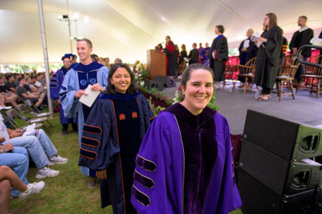 Faculty smile as they walk toward the stage