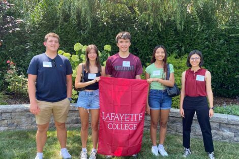 Incoming members of the Class of 2028 from the Lehigh Valley are smiling at the camera. They are holding a Lafayette flag.