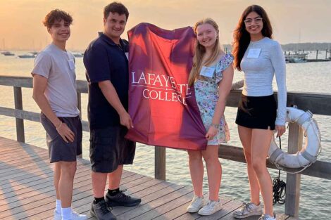 Incoming members of the Class of 2028 from Long Island are smiling at the camera. They are holding a Lafayette flag.