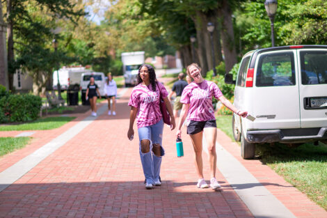 Two students walk, smiling in 