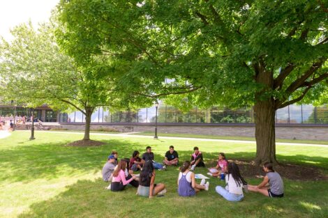 Students sit in a circle in front of Skillman Library