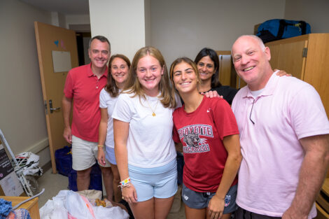 A family smiles as they move into a residence hall.