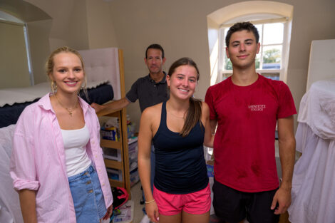 A family smiles as they move into a residence hall.