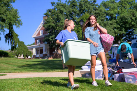 Two students carry bags and boxes