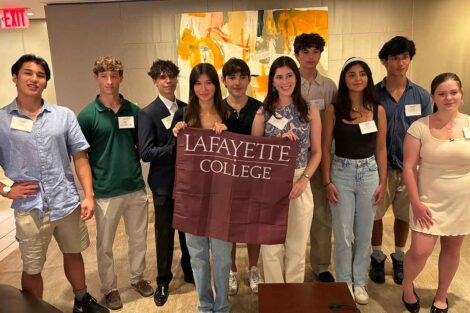 Incoming members of the Class of 2028 from New York City are smiling at the camera. They are holding a Lafayette flag.