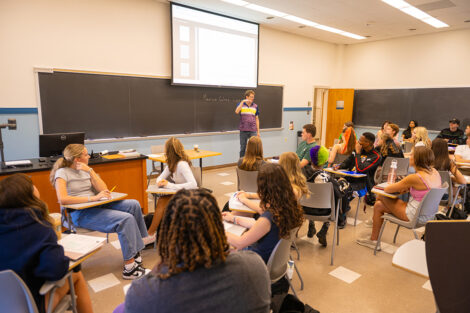 A professor teaches in front of a large screen.