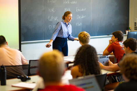 A professor teaches in a full classroom.