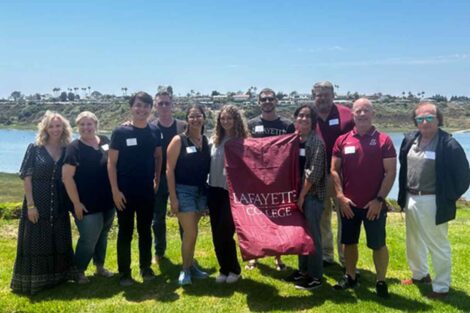 Incoming members of the Class of 2028 from Southern California are smiling at the camera. They are holding a Lafayette flag.