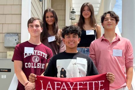 Incoming members of the Class of 2028 from the New Jersey shore area are smiling at the camera. They are holding a Lafayette flag.