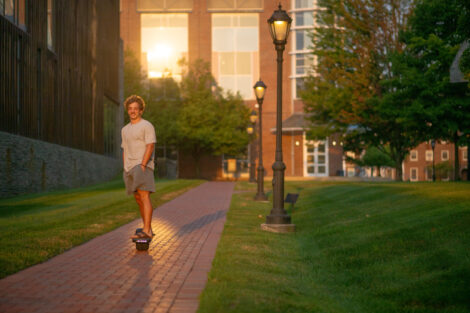 A person skateboards on a brick path at sunrise.