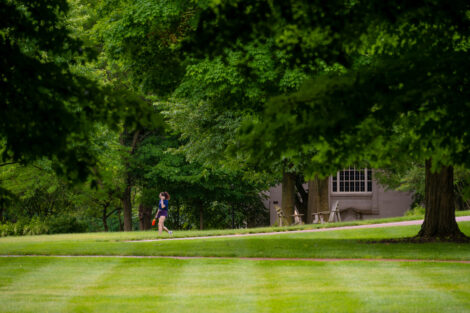 A student walks across a vibrant green quad on Lafayette College's campus.