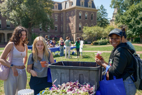 Students smile holding pots and plants.