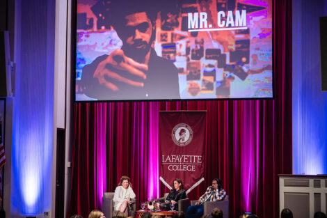 President Nicole Hurd, Jaye Fenderson, and Daveed Diggs speak on stage in Colton Chappel as a preview of The Class is shown on screen.