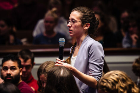 A student in a crowd stands up with a microphone to ask Daveed Diggs a question.