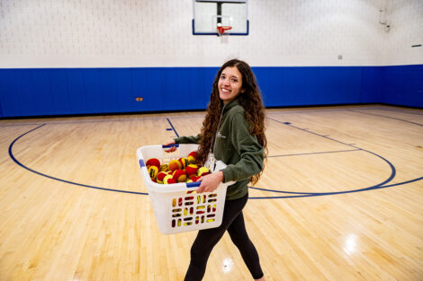 A Lafayette student carries a laundry basket filled with balls.