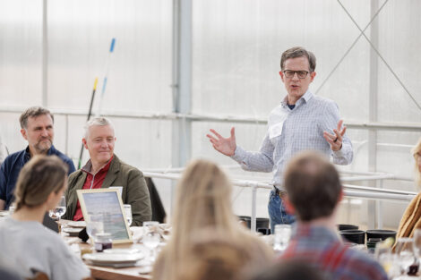 John Mulcahy ’87 is speaking to a crowd in the greenhouse at LaFarm.