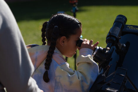 A young girl looks through a telescope set up in Anderson Courtyard during LV Space Fest.