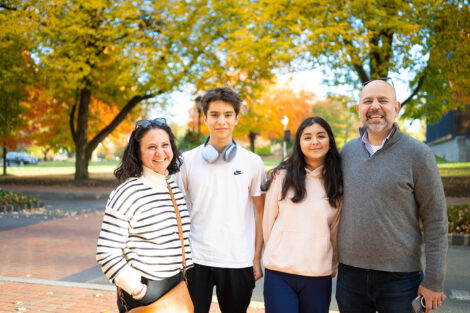 A family of four pose outside on the Quad.