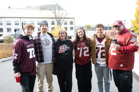 A group of six stand arm in arm outside before the football game.