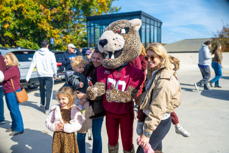 The leopard mascot is posing with a family.