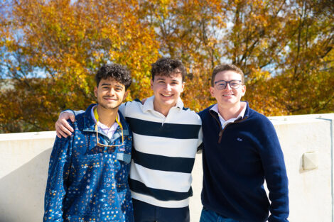 Three students stand arm in arm next to each other on Markle Parking Deck.