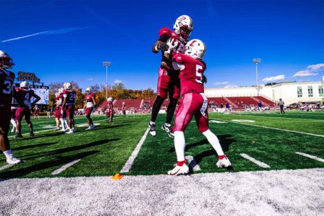 Two football players congratulate each other. One is lifting the other up in the air.