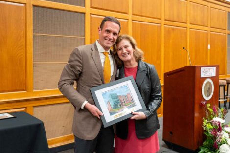 Jonathan Ellis '98 poses with President Nicole Hurd. They are holding a framed photo.