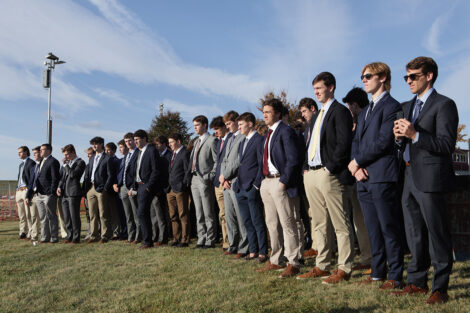 Members of the men's lacrosse team are standing in a line at the groundbreaking.