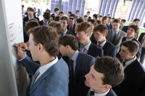 Members of the men's lacrosse team sign a beam in the Wallach Sports Performance and Lacrosse Center.