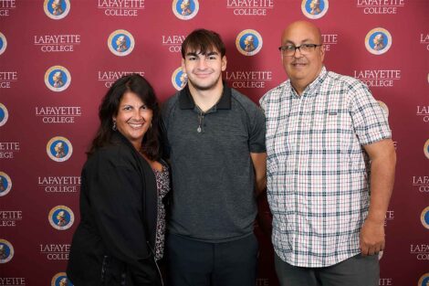 Three family members are standing in front of a Lafayette backdrop. They are smiling at the camera.