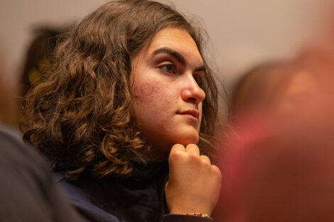 A student listens to speakers on stage.