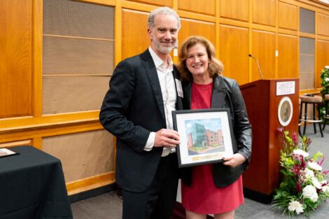 David S. MacKnight '94 is standing with President Nicole Hurd. They are holding a framed photo.