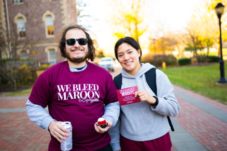 Two students smile, holding cupcakes.