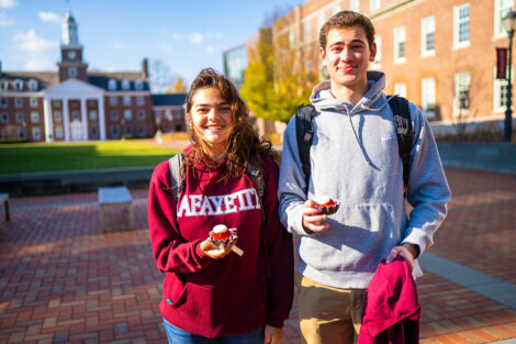 Two students smile, holding cupcakes.