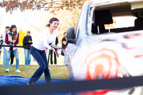 A student uses a sledgehammer on the Lehigh car.