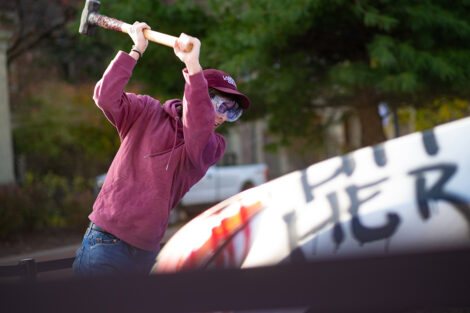 A student uses a sledgehammer on the Lehigh car.