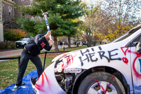 A student uses a sledgehammer on the Lehigh car.